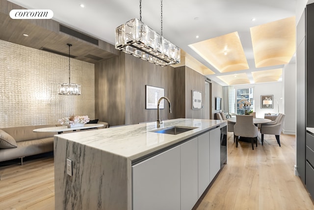 kitchen with an inviting chandelier, modern cabinets, open floor plan, and a sink