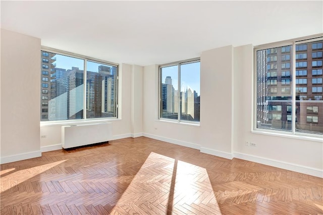 spare room featuring a view of city, radiator heating unit, and baseboards