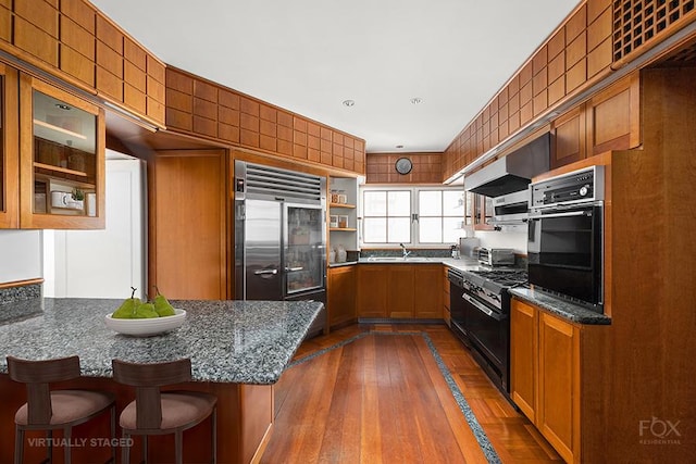 kitchen with dark stone counters, appliances with stainless steel finishes, a breakfast bar, and a peninsula