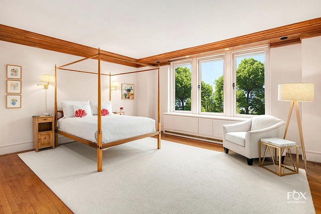 bedroom with baseboards, wood-type flooring, ornamental molding, and a baseboard radiator