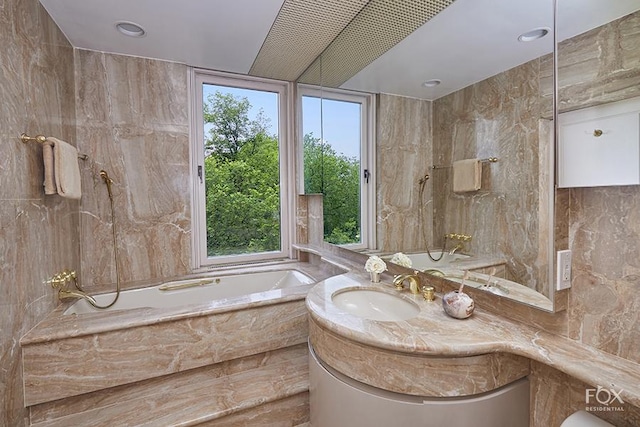 bathroom featuring tile walls, vanity, and a garden tub