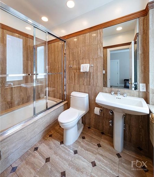 bathroom featuring enclosed tub / shower combo, recessed lighting, toilet, and tile walls