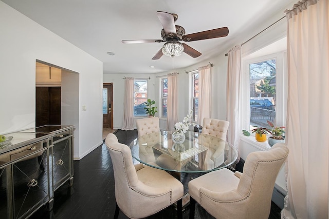 dining space featuring baseboards, a ceiling fan, a healthy amount of sunlight, and dark wood-style flooring