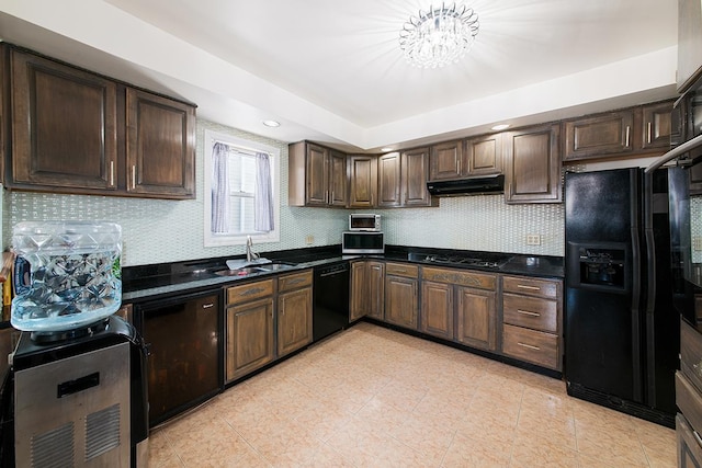 kitchen with dark countertops, backsplash, under cabinet range hood, black appliances, and a sink