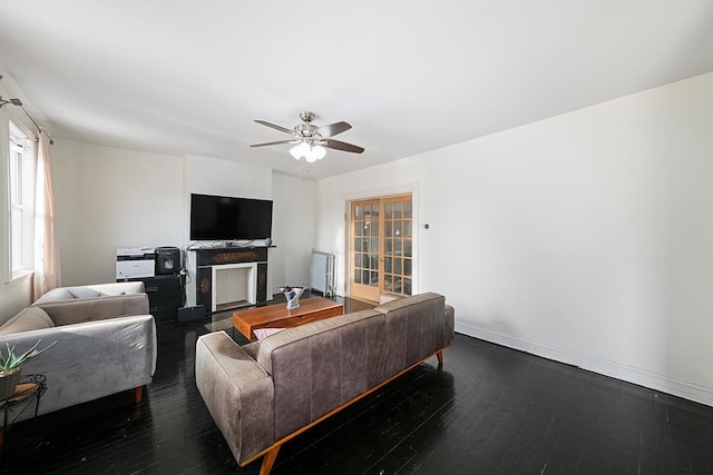 living room with a ceiling fan, baseboards, dark wood-style flooring, and a fireplace