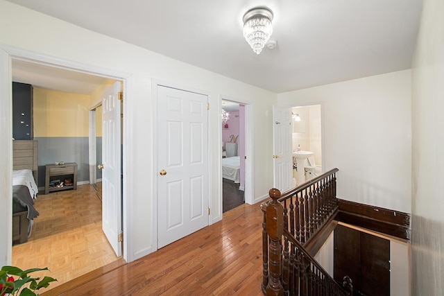 hall with parquet floors, an upstairs landing, and baseboards