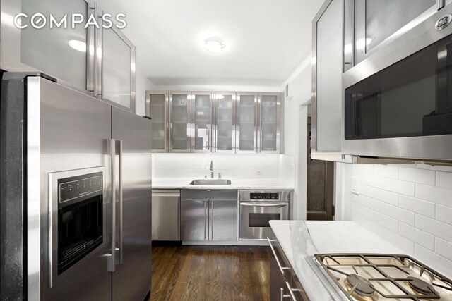 150 E 93rd St Unit 5B, New York City, NY 10128 - kitchen with stainless steel appliances, backsplash, light countertops, and dark wood finished floors