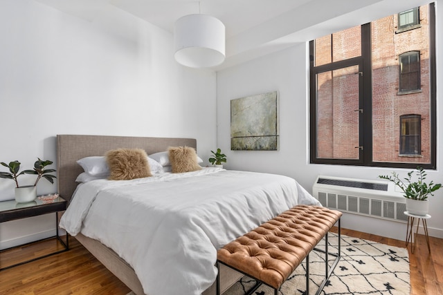 bedroom with radiator, baseboards, and wood finished floors