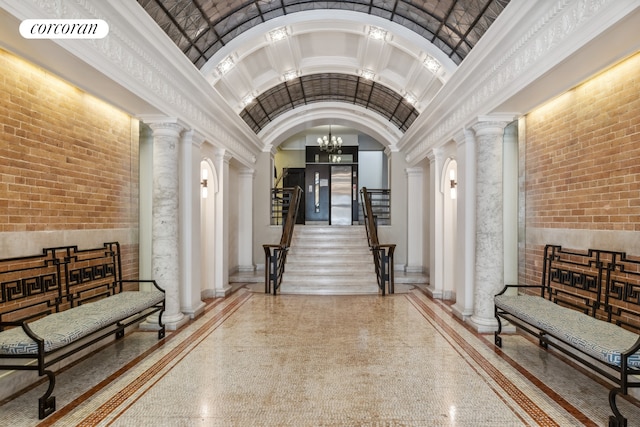 hall featuring visible vents, baseboards, ornate columns, lofted ceiling, and a chandelier