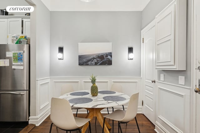 dining area featuring a wainscoted wall, dark wood-style floors, and a decorative wall