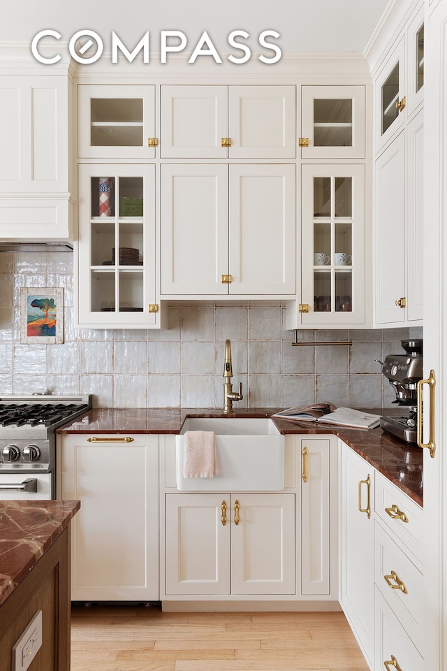 kitchen with dark stone countertops, backsplash, white cabinets, and a sink