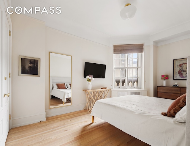 bedroom featuring ornamental molding, baseboards, and wood finished floors