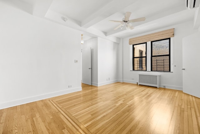 empty room featuring beamed ceiling, baseboards, light wood-style floors, and radiator heating unit