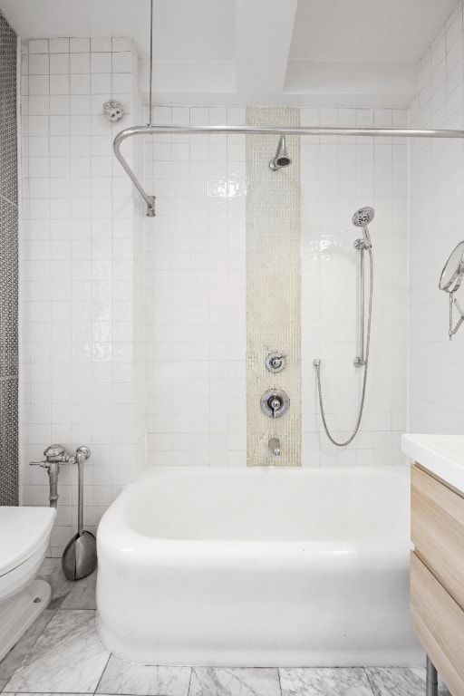 full bathroom featuring tile walls, toilet, bathtub / shower combination, marble finish floor, and vanity