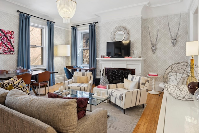 living area with a fireplace, wallpapered walls, an inviting chandelier, and wood finished floors