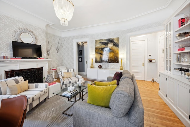 living room featuring a notable chandelier, light wood-style flooring, a fireplace, and wallpapered walls