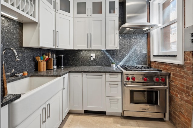 kitchen featuring designer stove, wall chimney exhaust hood, and white cabinetry