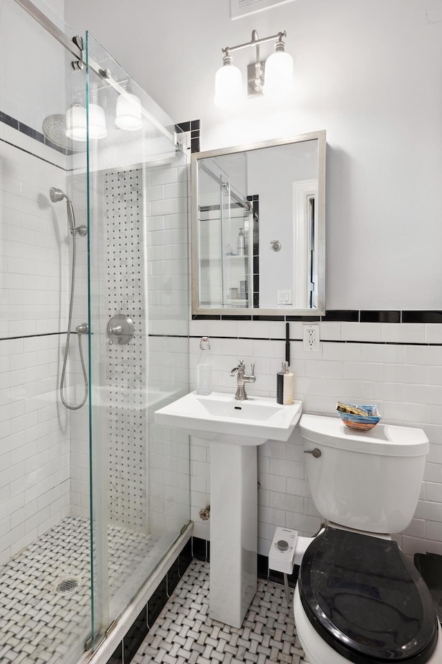 bathroom with tile patterned floors, a stall shower, toilet, and tile walls