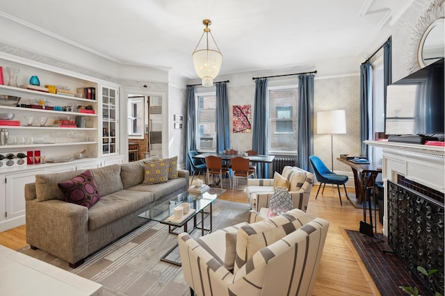 living area with wallpapered walls, a fireplace with flush hearth, light wood-type flooring, cooling unit, and a notable chandelier