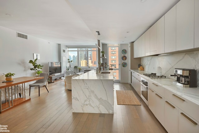 kitchen featuring light wood-style flooring, appliances with stainless steel finishes, visible vents, and backsplash