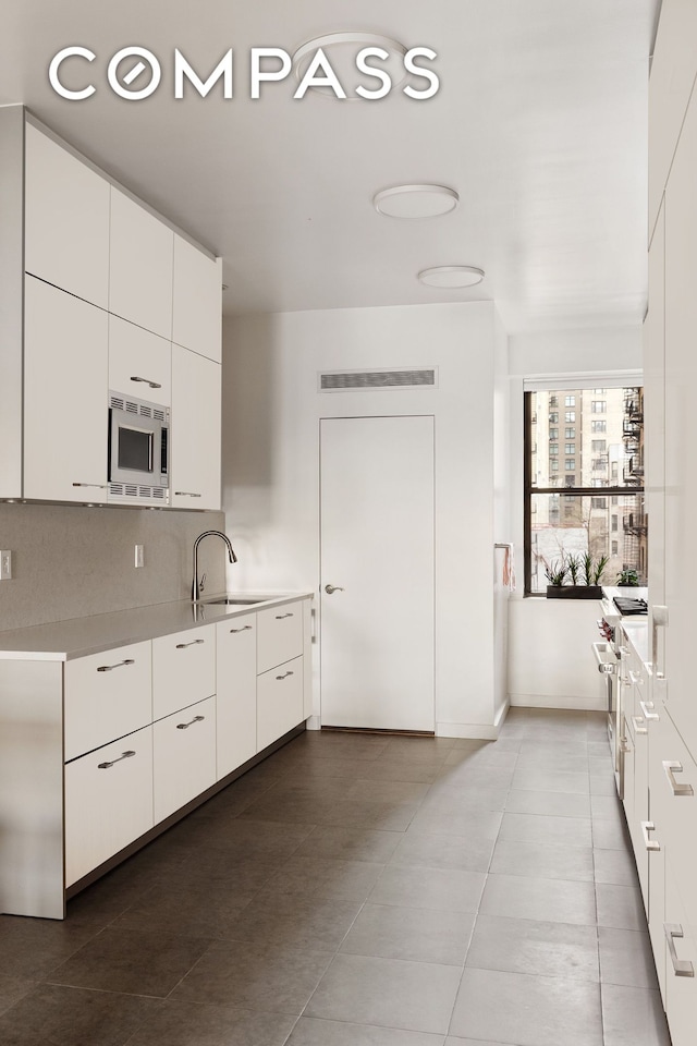 kitchen featuring light countertops, white cabinets, appliances with stainless steel finishes, and a sink