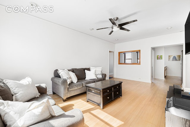 living room with baseboards, ceiling fan, and light wood finished floors