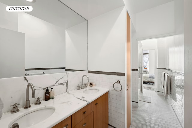 bathroom featuring visible vents, tile walls, ensuite bathroom, and a sink