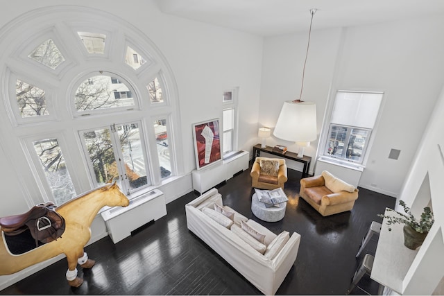 living area with baseboards, a towering ceiling, and dark wood-style flooring