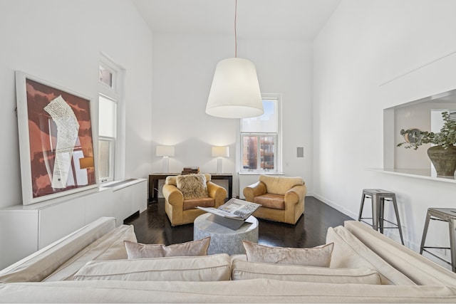 living area featuring baseboards, a towering ceiling, and dark wood-style flooring