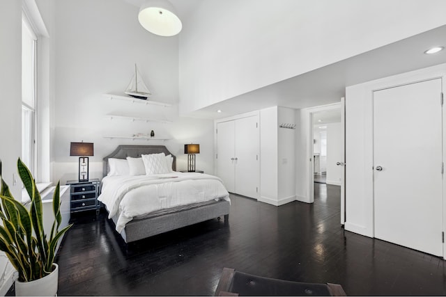 bedroom with dark wood finished floors, recessed lighting, and a towering ceiling