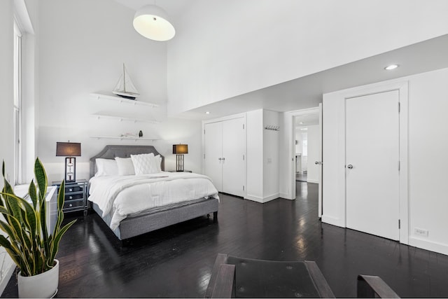 bedroom featuring dark wood finished floors, a high ceiling, recessed lighting, and baseboards