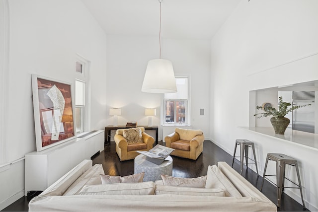 living room featuring dark wood-style floors, a high ceiling, and baseboards