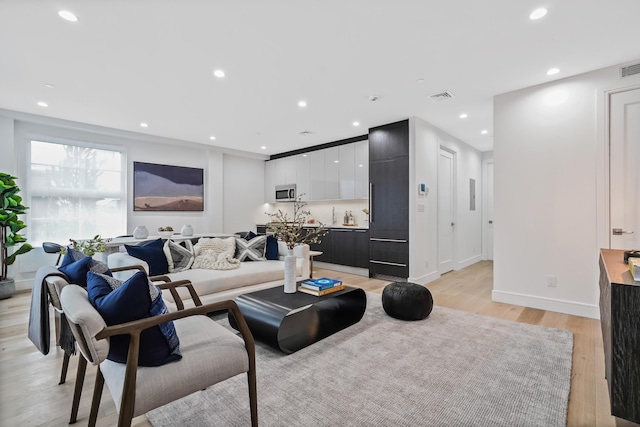 living room with recessed lighting, visible vents, baseboards, and light wood-style flooring