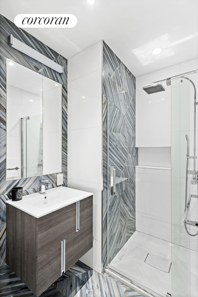 bathroom with a stall shower, vanity, and tile walls