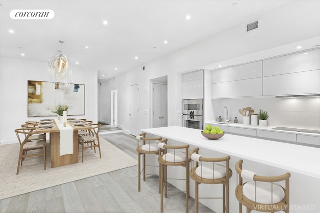 kitchen featuring visible vents, modern cabinets, a sink, light wood-style floors, and cooktop