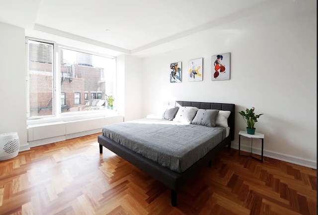 bedroom featuring baseboards, a tray ceiling, and multiple windows