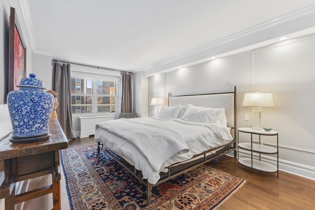 bedroom with wood finished floors, baseboards, and ornamental molding