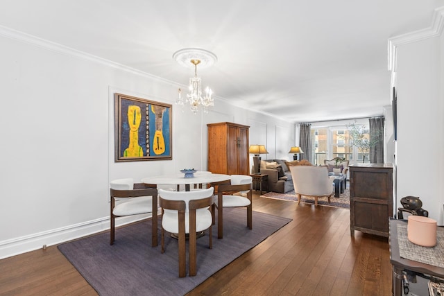 dining area with dark wood-style floors, a chandelier, baseboards, and ornamental molding