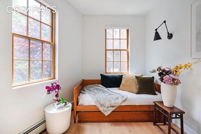 bedroom with wood finished floors, a baseboard heating unit, and baseboard heating