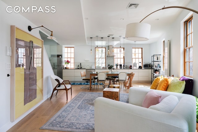 living area with light wood-style floors, baseboards, and visible vents