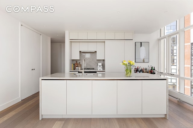 kitchen featuring light countertops, a wealth of natural light, light wood-style floors, and backsplash