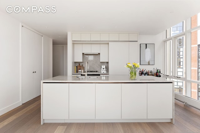5 Beekman St Unit 21B, New York City, NY 10038 - kitchen with light countertops, light wood-style flooring, decorative backsplash, white cabinetry, and a spacious island