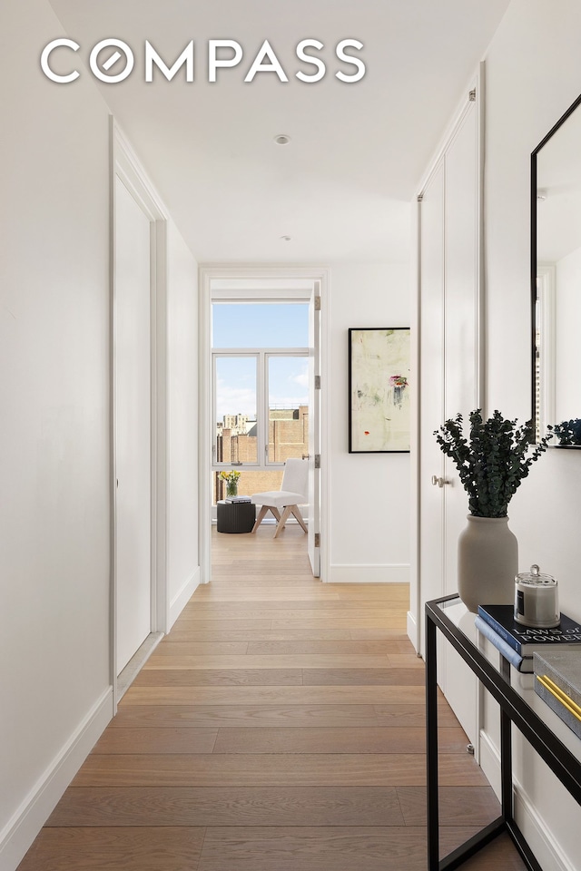 hallway featuring light wood-style flooring and baseboards