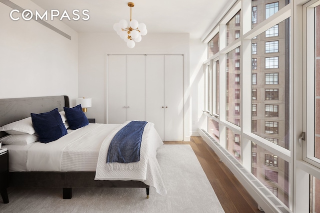 bedroom featuring an inviting chandelier, wood finished floors, a closet, and expansive windows