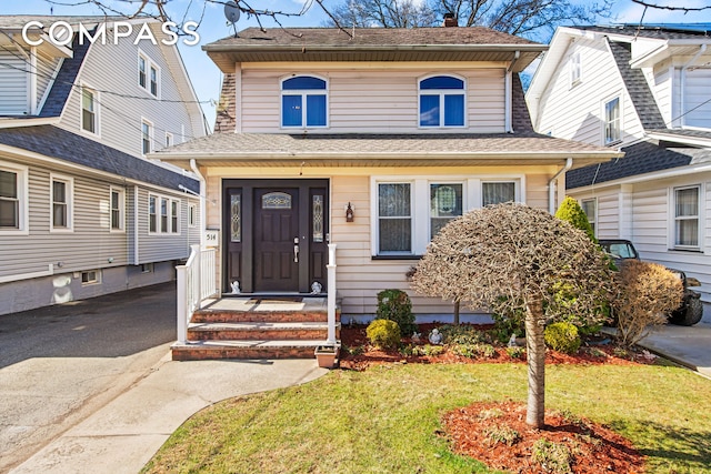 view of front facade with aphalt driveway, a front yard, and roof with shingles