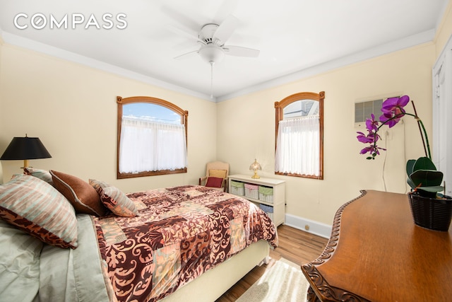 bedroom featuring multiple windows, crown molding, and wood finished floors