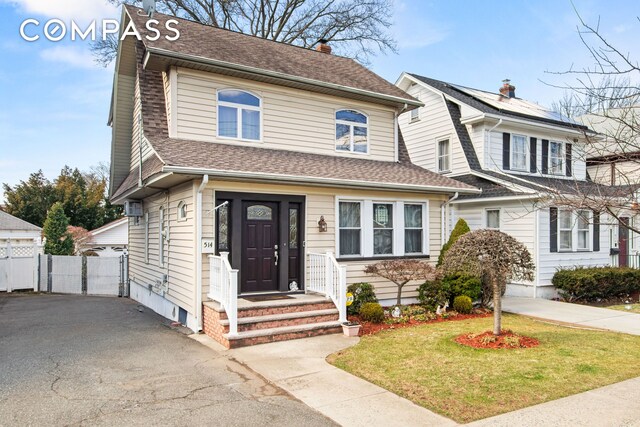 view of front of property featuring a front yard, fence, and roof with shingles