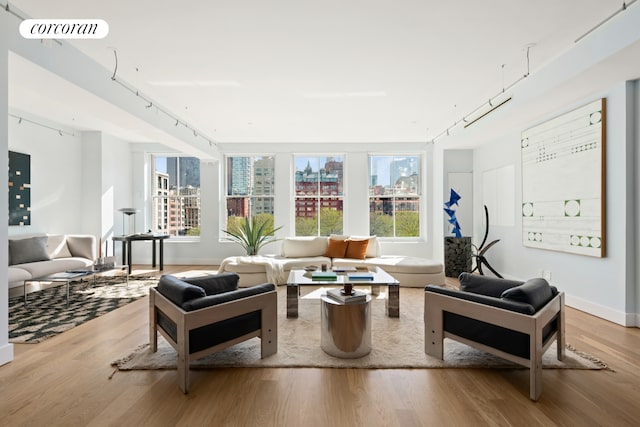 living room featuring wood finished floors, a view of city, a healthy amount of sunlight, and visible vents