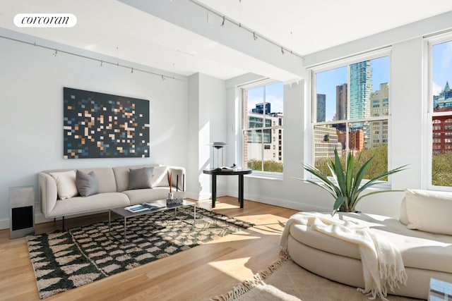 living area with visible vents, a view of city, track lighting, wood finished floors, and baseboards