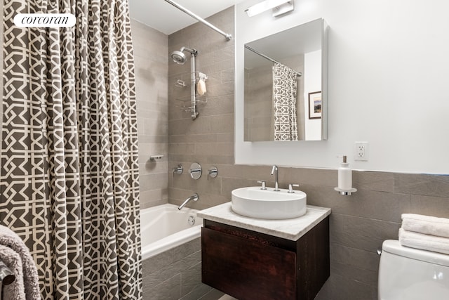 full bath with vanity, tile walls, toilet, and tiled shower / bath